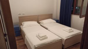 2 łóżka pojedyncze w małym pokoju z niebieskimi zasłonami w obiekcie Villa Eden 111, Perla Resort, Bay of Lalzi w Durrës