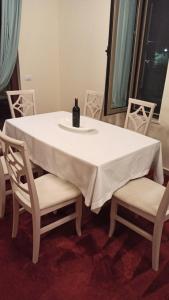 - une table blanche avec une bouteille de vin et 2 chaises dans l'établissement Villa Eden 111, Perla Resort, Bay of Lalzi, à Durrës
