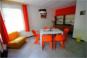 a dining room with a white table and orange chairs at DDR Bungalow direkt am Strand auf Rügen in Dranske