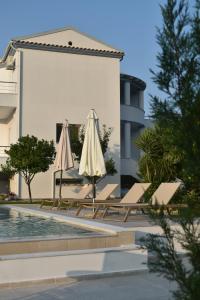 due ombrelloni bianchi seduti accanto alla piscina di Olgas Luxury Villa, Corfu Greece a Evropoúloi