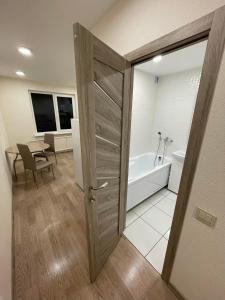 uma casa de banho com uma porta aberta para uma casa de banho com uma banheira em 1 kambario butas self check in em Siauliai