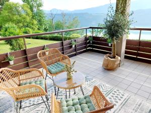 een patio met rieten stoelen en een tafel op een balkon bij Panoramasuite am Millstättersee in Dellach
