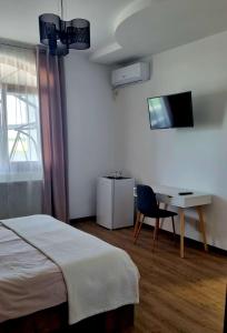1 dormitorio con 1 cama, escritorio y TV en VILA DENISA, en Limanu