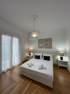 a white bedroom with a large white bed with two tables at Vibrant Urban Getaway: Modern 1-Bedroom near Bars, Parks, and Metro in Athens