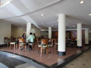 a group of people sitting at tables in a restaurant at Hotel Wisata in Palembang