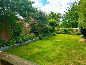 a garden with a lawn with flowers and plants at Tanyard Cottage - Whixley, York, North Yorkshire in York