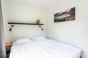 a bedroom with a bed with white sheets at Bosweg 18-B in Zoutelande