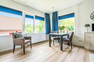 a dining room with a table and chairs and windows at Bosweg 18-B in Zoutelande