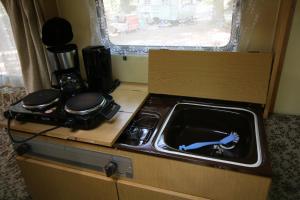 a kitchen with a stove and a sink in a box at DDR Kult Wohnwagen direkt am Strand in Kreptitz