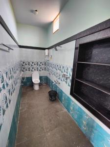 a bathroom with a toilet and tiles on the walls at Aditya Tourist Home in Hampi