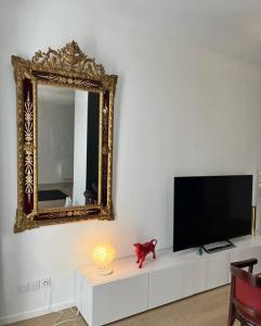 einen Spiegel und eine Katze auf einer Kommode mit einem TV in der Unterkunft Vigne et mer-Spacieux Appartement Haussmannien-2chambres-Wifi in Béziers