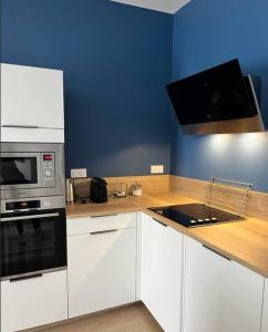 een keuken met witte apparatuur en een blauwe muur bij Vigne et mer-Spacieux Appartement Haussmannien-2chambres-Wifi in Béziers