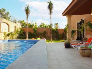 a swimming pool in front of a house with palm trees at Royal Mansion with private pool in sheikh zayed Compound families in Sheikh Zayed