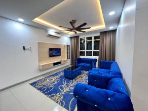 sala de estar con sofá azul y TV en Qaisara Qais Homestay en Kuala Terengganu