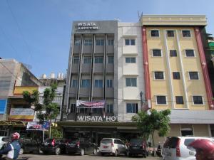 ein Gebäude auf einer Straße mit Autos auf einem Parkplatz in der Unterkunft Hotel Wisata in Palembang