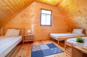 a log cabin with two beds and a window at Domki LUX in Jarosławiec