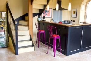 a kitchen with a bar with pink stools at a counter at The Sunday Schoolroom in Sherborne