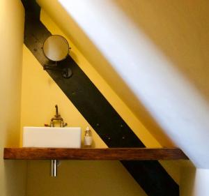 a bathroom with a sink and a mirror on a shelf at The Sunday Schoolroom in Sherborne