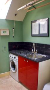 a kitchen with a sink and a washing machine at The Sunday Schoolroom in Sherborne
