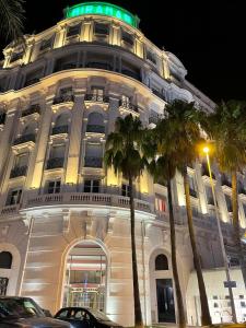 un grand bâtiment blanc avec des palmiers devant lui dans l'établissement New - cosy & nice Apartment in Palais Miramar, à Cannes