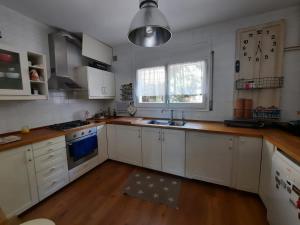 a kitchen with white cabinets and a clock on the wall at Caldetas in Caldes d'Estrac