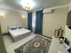 a bedroom with a bed with blue pillows and a rug at Hotel Astam in Kostanay