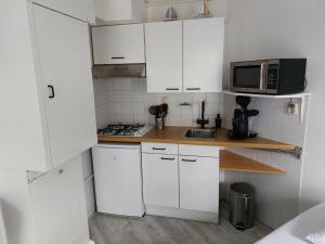 uma pequena cozinha com armários brancos e um micro-ondas em genieten texel 8 em De Koog