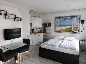 een slaapkamer met een bed, een tafel en een televisie bij genieten texel 8 in De Koog