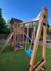 a wooden playground with two swings and a slide at Wellness chata Kozička in Klokočov