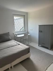 a bedroom with a bed and a desk and a window at Casa Móre GRAY in Niederalm