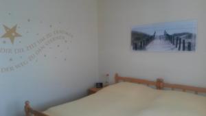 a bedroom with a bed with a picture on the wall at Bungalow am Südstrand Staberdorf mit Meerblick in Staberdorf