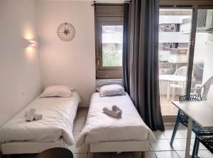 - 2 lits dans une petite chambre avec fenêtre dans l'établissement Résidence Graziella Studio 121, à Juan-les-Pins