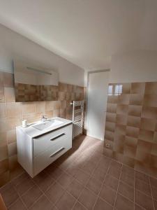 a bathroom with a white sink and a tile floor at Maison au coeur du Périgord Vert in Javerlhac-et-la-Chapelle-Saint-Robert