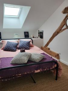 Schlafzimmer mit einem Bett mit lila Bettwäsche und Kissen in der Unterkunft Les naturelles in Saint-Aubin-de-Locquenay