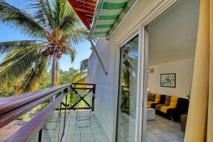 a house with a balcony with a palm tree at Studio La Tortue in Saint-Gilles les Bains