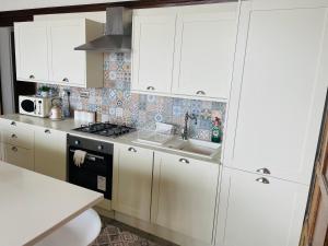 cocina con armarios blancos, fregadero y fogones en 1 Bedroom Sea side luxury en New Brighton