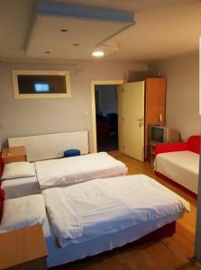 a hotel room with three beds and a television at Viktorija Nova in Kanjiža