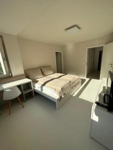biała sypialnia z łóżkiem i biurkiem w obiekcie Casa Móre BEIGE w mieście Niederalm