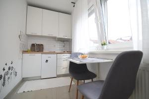 cocina con armarios blancos, mesa y sillas en GretaNola studio in Zagreb, parking, self check-in, en Zagreb