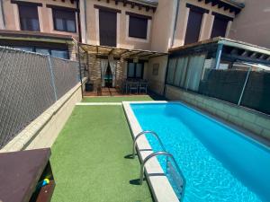 a swimming pool with green grass next to a building at La espiga de la Mata in Segovia