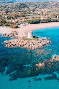 een eiland in de oceaan met een vuurtoren op een strand bij SA DOMU DE S'ORTU in Bari Sardo