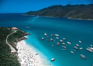 a group of boats in the water on a beach at Arraial Praia Ap - Residence Club Praia dos Anjos in Arraial do Cabo