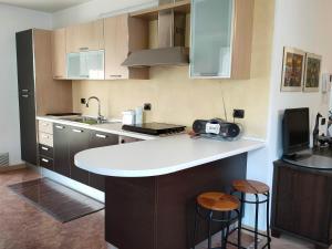 eine Küche mit einer Spüle und einer Theke mit Hockern in der Unterkunft Appartamento al Parco, Brentonico in Brentonico