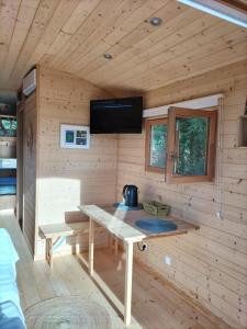 Cabaña de madera con mesa y TV en la pared en La roulotte de Jane, en Margon