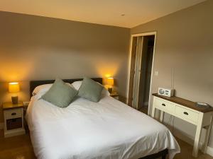 a bedroom with a large white bed with two lamps at Beautiful self-catering cottages, Ribble Valley in West Bradford