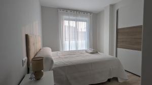 ein weißes Schlafzimmer mit einem Bett und einem Fenster in der Unterkunft Playa de Vilariño in Cangas