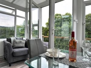 a living room with a couch and a table with a bottle of wine at Sleek Skyward Serenity 2bed with Pool Table - Ystrad in Llwyn-y-pia