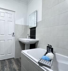 a white bathroom with a tub and a sink at Sleek Skyward Serenity 2bed with Pool Table - Ystrad in Llwyn-y-pia
