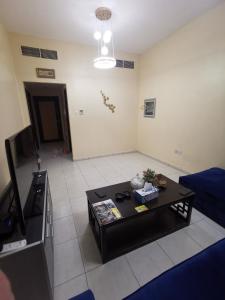 a living room with a table and a tv at Furnished 1bhk with all needs in Ajman 
