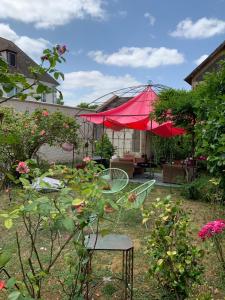 a patio with red umbrellas in a garden at Charmant logement centre-ville in Houdan